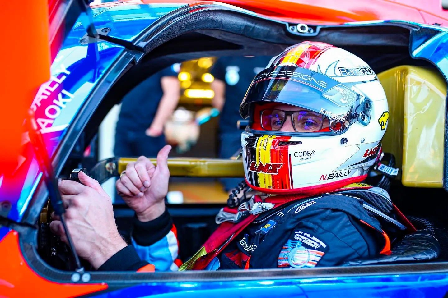 Nigel Bailly dans son véhicule de course faisant un signe du pouce vers le haut.